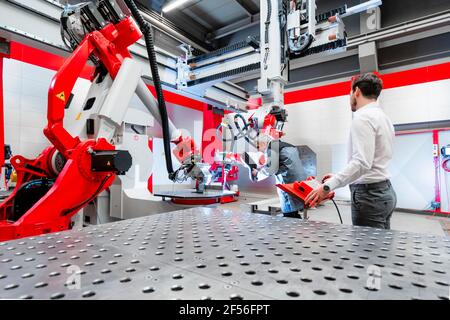 Soudeur avec écran de soudage travaillant sur des machines en usine Banque D'Images