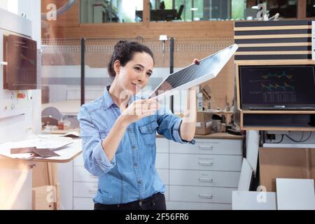 Femme entrepreneur analysant le modèle de panneau solaire en usine Banque D'Images