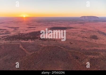 Australie, territoire du Nord, vue aérienne du paysage désertique du parc national d'Uluru-Kata Tjuta au lever du soleil avec Uluru en arrière-plan Banque D'Images