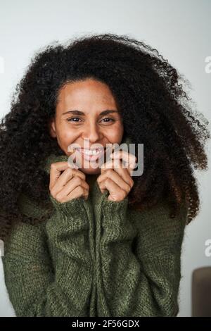 Femme aux cheveux bouclés en chandail sur fond gris Banque D'Images