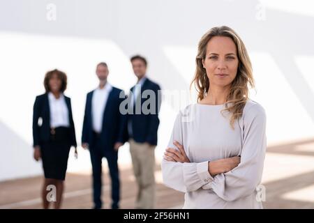 Femme d'affaires confiante qui se tient debout avec ses collègues en arrière-plan terrasse de bureau Banque D'Images