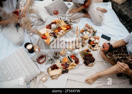 Les jeunes femmes qui ont de la nourriture et des boissons tout en étant assis sur une couverture sur la terrasse du bâtiment Banque D'Images