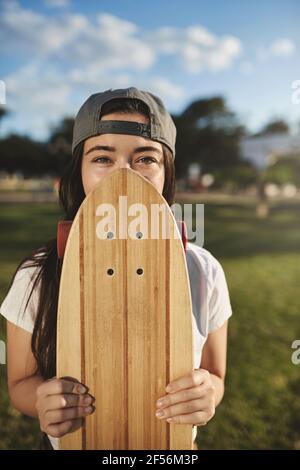 Photo verticale insouciante adolescente hipster fille dans le vivaneau gris, couverture face avec panneau de bois de sou, les yeux souriant et regarder l'appareil photo, adolescent appréciant Banque D'Images