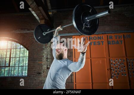 Un athlète souriant levant la barbell dans un studio de sport Banque D'Images