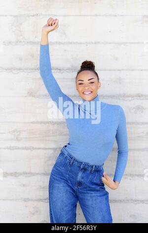 Femme insouciante qui danse à la main en se tenant contre le mur Banque D'Images
