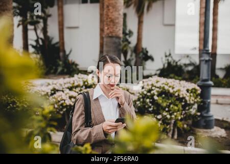 Femme d'affaires réfléchie utilisant un téléphone intelligent Banque D'Images