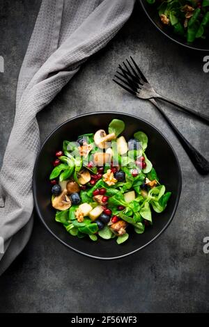 Salade d'automne composée d'agneaux, de laitue, de champignons, de poires frites, de bleuets, de graines de grenade et de noix Banque D'Images