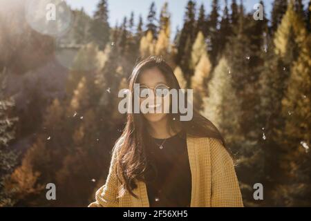 Jeune femme portant des lunettes de soleil souriant en forêt Banque D'Images