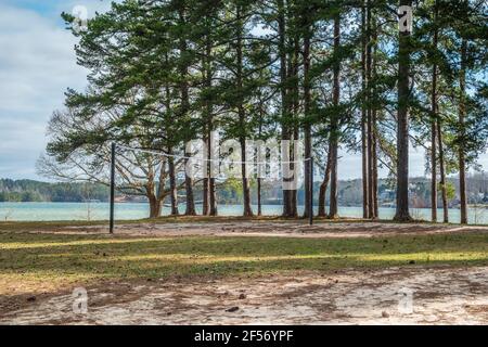 Filet de volley installé sur la plage à l' bord de lac dans un parc avec des arbres et le lac dedans l'arrière-plan d'une journée ensoleillée au printemps Banque D'Images