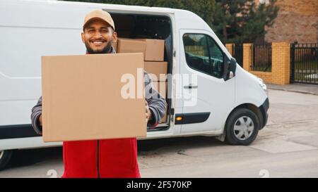 Pack de livraison Indian man. Tenir la boîte en carton devant la camionnette. Photo de haute qualité Banque D'Images