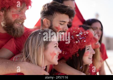 Un fan de football hurle, avec des chemises rouges à l'intérieur du stade . Groupe de jeunes très enthousiastes au sujet du football. Concept sport et fun Banque D'Images