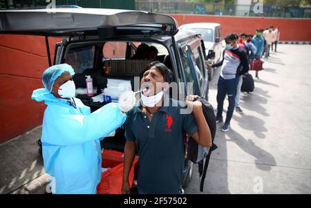 Delhi, Inde. 24 mars 2021. Un professionnel de la santé prélève un écouvillon auprès d'un homme pour un test COVID-19 dans un terminus d'autobus à Delhi, en Inde, le 24 mars 2021. Le nombre de cas de COVID-19 en Inde a atteint 11,734,058 mercredi, alors que 47,262 nouveaux cas ont été signalés dans tout le pays, selon les derniers chiffres publiés par le ministère fédéral de la Santé. Credit: STR/Xinhua/Alay Live News Banque D'Images