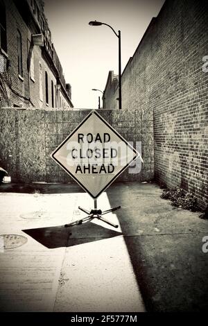 Route fermée devant le panneau. Allée bloquée avec des bâtiments en briques de chaque côté. Banque D'Images