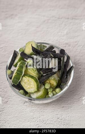 Le concept de congélation de la récolte à la maison. Plaque transparente avec haricots verts et pois courgettes congelés. Banque D'Images