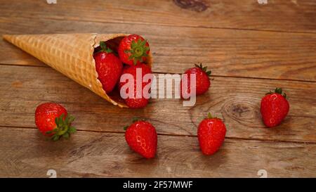 Cône de crème glacée avec fraises sur fond de bois Banque D'Images