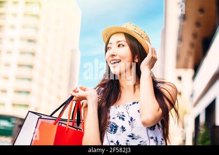 Bonne jeune femme tenant des sacs de shopping dans la rue Banque D'Images