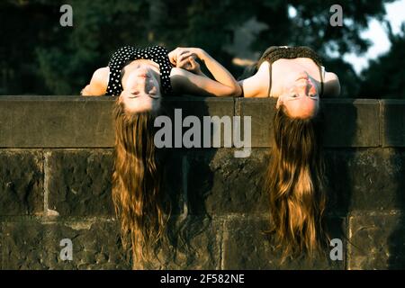 Jeunes filles allongé sur une dalle de pierre avec de longs cheveux suspendus au coucher du soleil. Banque D'Images