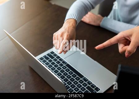 Les doigts des deux femmes d'affaires ont pointé sur l'écran de l'ordinateur portable pour analyser les données de l'entreprise. Banque D'Images