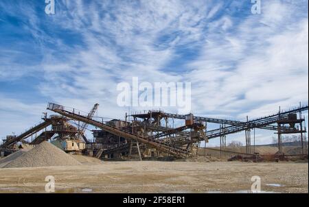 Machines de concassage, concasseur de roche de type cône, transportant des pierres de gravier de granit broyées dans une carrière d'exploitation minière à ciel ouvert. Usine de traitement pour la pierre concassée et Banque D'Images