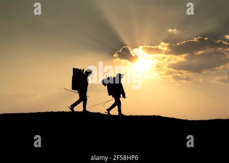 Ville de Pleiku, province de Gia Lai, Vietnam - 6 mars 2021 : deux agriculteurs de l'Ede collectent du bois de chauffage sur leur chemin, au coucher du soleil, dans la ville de Pleiku, province de Gia Lai, Banque D'Images