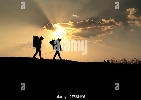 Ville de Pleiku, province de Gia Lai, Vietnam - 6 mars 2021 : deux agriculteurs de l'Ede collectent du bois de chauffage sur leur chemin, au coucher du soleil, dans la ville de Pleiku, province de Gia Lai, Banque D'Images