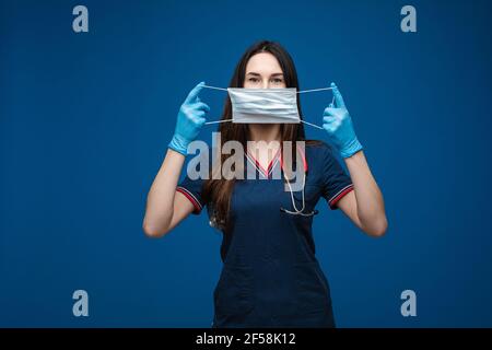 Médecin avec un masque aseptique dans les mains devant son visage. Banque D'Images