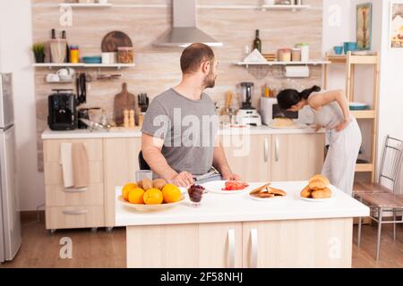 Femme utilisant un four à micro-ondes le matin pour préparer le petit déjeuner pour son mari. Jeune femme de ménage à la maison cuisinant le repas du matin, gai avec affection et amour Banque D'Images