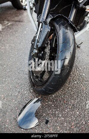 Cassé un morceau d'aile en plastique noir de la moto couché sur une route asphaltée après une collision de deux véhicules Banque D'Images