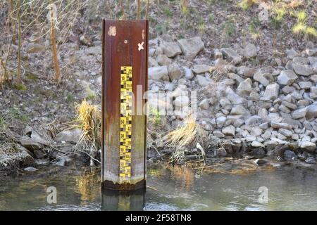 Marqueur jaune métrique de niveau d'inondation dans une rivière à faible niveau d'eau niveau Banque D'Images