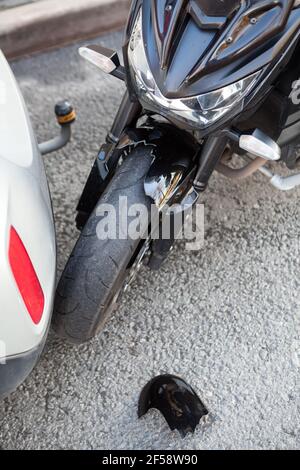 Blessures causées par une collision entre une moto et une voiture, vue rapprochée d'un accident de la route avec des pièces cassées d'une aile en plastique Banque D'Images