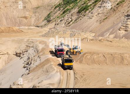 Chargeur frontal sur roues pour charger du sable dans un camion à benne basculante lourde, dans la carrière minière en ouvert. Le camion à benne basculante transporte le sable dans une mine à ciel ouvert. Carrière dans laquelle Banque D'Images