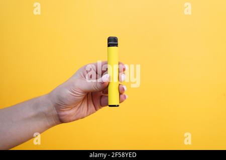 Cigarette lectronique jaune jetable dans la main femelle. Arrire-plan  jaune vif Photo Stock - Alamy