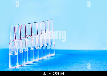 Ampoules médicales pour injection sur fond bleu. Ampoules en verre épars avec médicament sur la table. Médicaments et traitement de la maladie, pharmacolog Banque D'Images