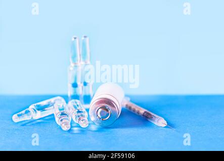 Ampoules médicales pour injection, flacon et seringue sur fond bleu. Ampoules en verre et flacons de médicaments sur la table. Médicaments et traitement des maladies Banque D'Images