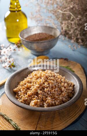 Einkorn, Triticum monococcum, boulgur de blé Siyez.Bulgur pilaf fait avec siyez bulgur dans une plaque sur fond de bois. Banque D'Images