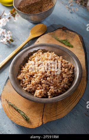 Einkorn, Triticum monococcum, boulgur de blé Siyez.Bulgur pilaf fait avec siyez bulgur dans une plaque sur fond de bois. Banque D'Images