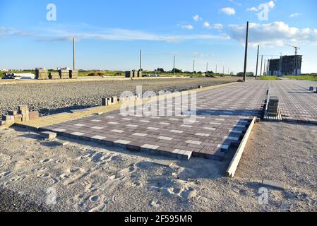 Processus d'installation de briques de pavage dans la zone piétonne de la ville. Pose de dalles et de bordures sur le chantier. Crier le sable pour l'installation Banque D'Images