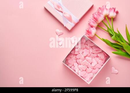 Composition festive avec de belles fleurs de tulipes délicates en boîte ronde rose sur fond clair. Flat lay, espace de copie. Carte de vœux du printemps. Banque D'Images