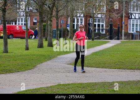 Ashford, Kent, Royaume-Uni. 25 mars 2021. Météo au Royaume-Uni : les gens apprécient le parc Victoria à Ashford, dans le Kent, tandis que les intervalles ensoleillés offrent un agréable soleil de printemps chaud. Un jogging dans un haut lumineux court autour du parc Victoria. Crédit photo : Paul Lawrenson /Alay Live News Banque D'Images