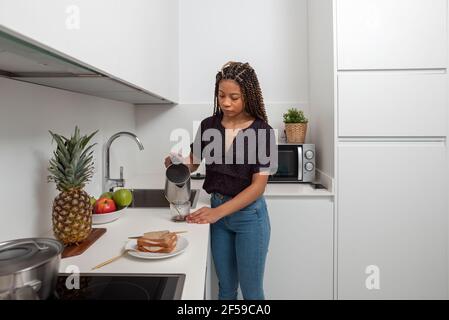 Femme préparant du café soluble à la maison tout en préparant un petit déjeuner sain dans la cuisine Banque D'Images