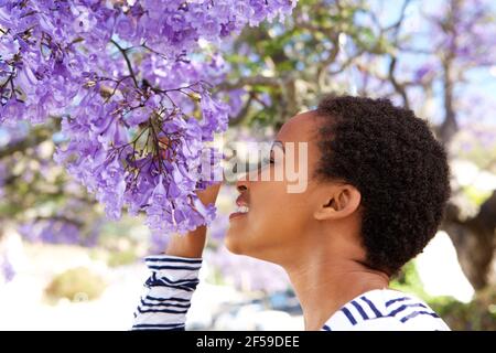 Portrait d'une jeune femme noire qui sent des fleurs sur l'arbre Banque D'Images