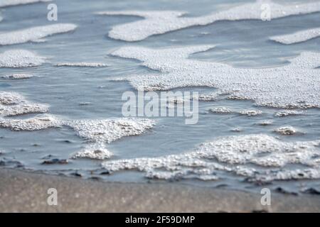 Gros plan de la mousse de mer des vagues sur le rivage Banque D'Images