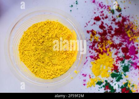 Holi couleurs poudre dispersée sur fond blanc avec jaune ou peela rang à l'avant. Vue de dessus des couleurs holi pour le festival indien de la couleur. Arrière Banque D'Images