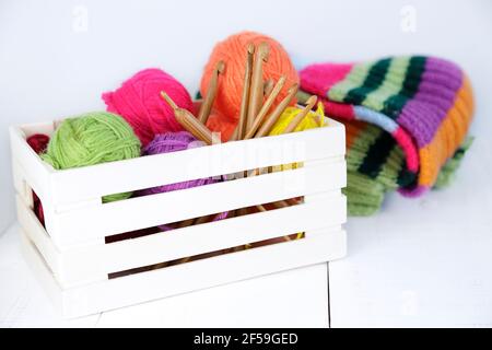 Boîte en bois avec crochets en crochet de bambou naturel et boules de laine de différentes couleurs. Banque D'Images