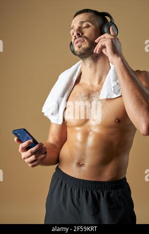 Athlète caucasien adulte avec smartphone à la main isolé sur le jaune arrière-plan Banque D'Images