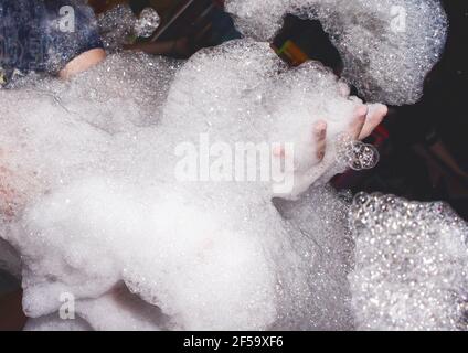 Beaucoup de savon suds dans les mains d'un homme à une fête de mousse dans un fond de boîte de nuit. Banque D'Images