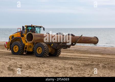 Volvo L180H Optishift Wheel Loader transportant de gros tuyaux le long de la plage pour les travaux de réapprovisionnement de plage à Bournemouth et Poole Beaches, Dorset UK en mars Banque D'Images