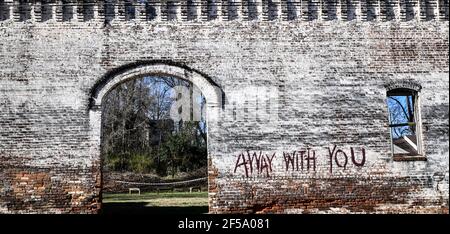 vieux mur de briques abîmé autour du cimetière de la petite ville Banque D'Images