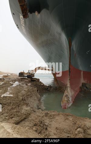 (210325) -- LE CAIRE, le 25 mars 2021 (Xinhua) -- une pelle hydraulique travaille sur le site d'un navire à conteneurs piégé sur le canal de Suez en Égypte le 25 mars 2021. La navigation dans le canal de Suez a été suspendue temporairement jusqu'à la fin des travaux de re-flottaison sur un navire ancré dans un nouveau cours, a déclaré jeudi Oussama Rabie, président de l'Autorité du canal de Suez (SCA). Le navire à conteneurs portant le drapeau du Panama, d'une capacité de 224,000 tonnes, a été mis à la terre tôt mardi dans le nouveau passage après avoir perdu la capacité de conduire dans des vents violents et une tempête de poussière, a déclaré l'ACR mercredi dans une déclaration. (Canal de Suez autorisé Banque D'Images