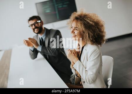 Groupe multiethnique de gens d'affaires travaillant ensemble et applaudissant après réunion réussie au bureau Banque D'Images